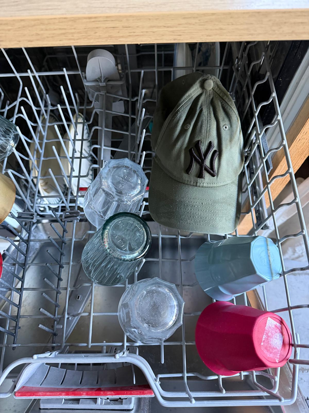 Casquette New York Yankees kaki posée dans un lave-vaisselle, entourée de verres
