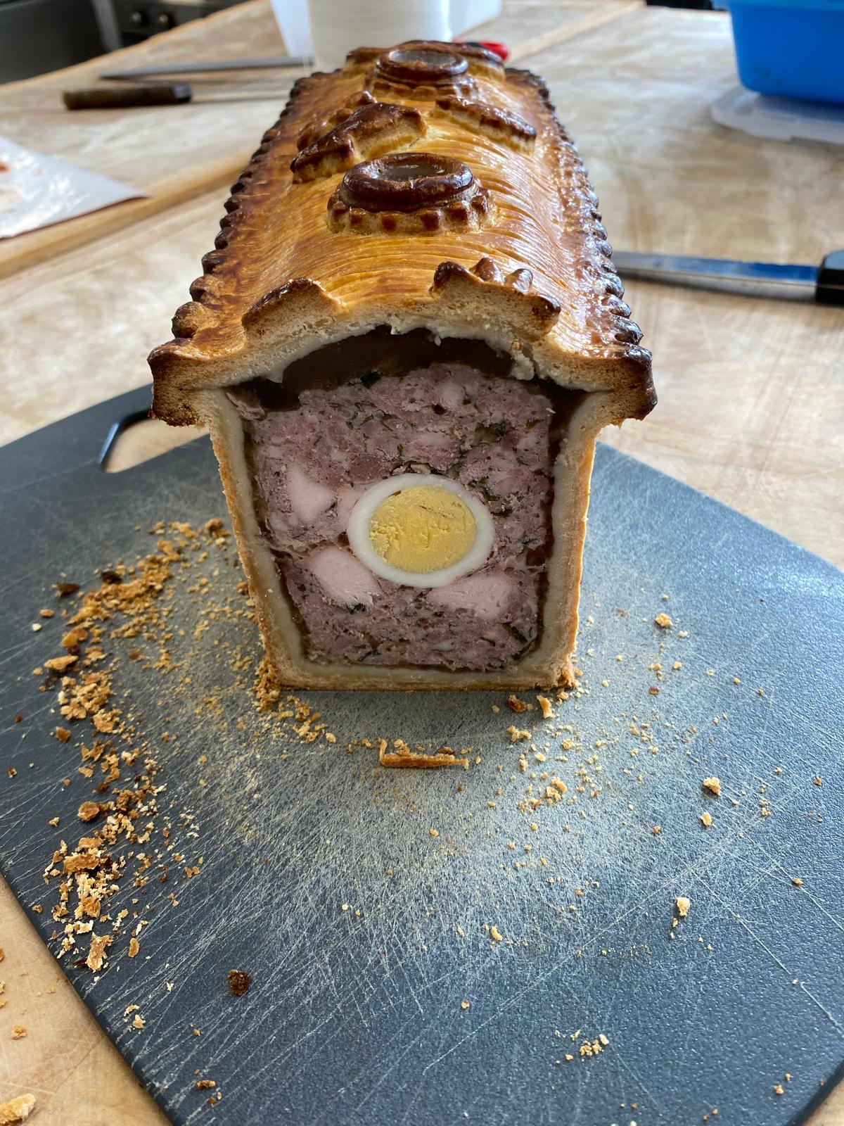 Pâté en croûte décoré, tranché pour révéler la farce et un œuf dur au centre