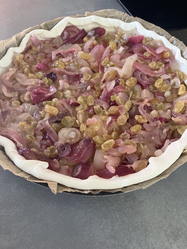 Tarte aux oignons rose de Roscoff garnie de raisins secs, avant cuisson